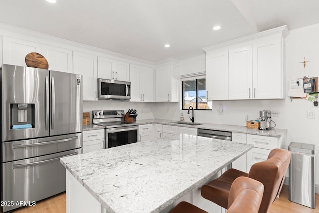 kitchen with stainless steel appliances, white cabinetry, a kitchen island, and sink