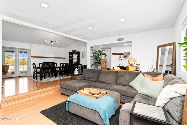 living room featuring wood-type flooring, vaulted ceiling with beams, a chandelier, and french doors