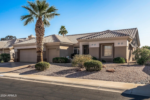 view of front of property featuring a garage, a tiled roof, concrete driveway, and stucco siding