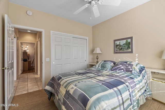 bedroom with ceiling fan, light tile patterned floors, and a closet