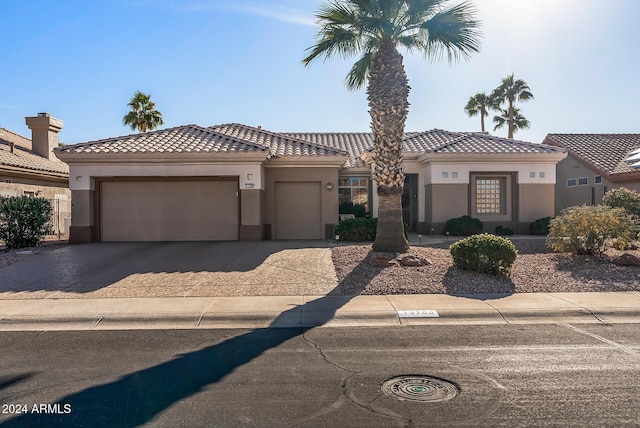 mediterranean / spanish house featuring a garage, driveway, a tiled roof, and stucco siding