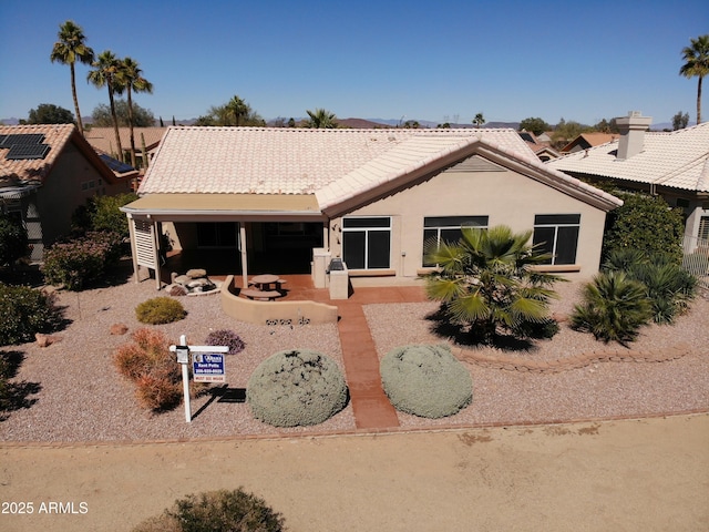 back of property with a patio area, stucco siding, and a tiled roof