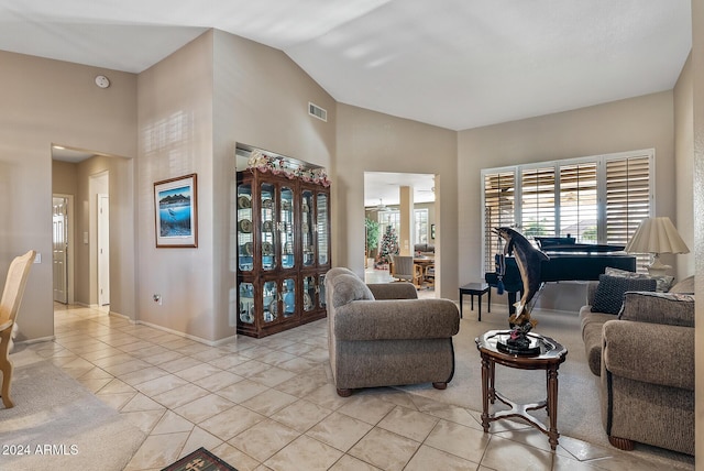 living area featuring light tile patterned floors, high vaulted ceiling, visible vents, and baseboards