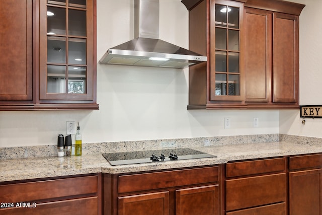 kitchen featuring black electric cooktop, light stone counters, and wall chimney range hood