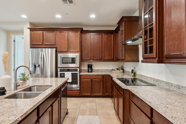 kitchen featuring appliances with stainless steel finishes, sink, light stone countertops, and wall chimney range hood