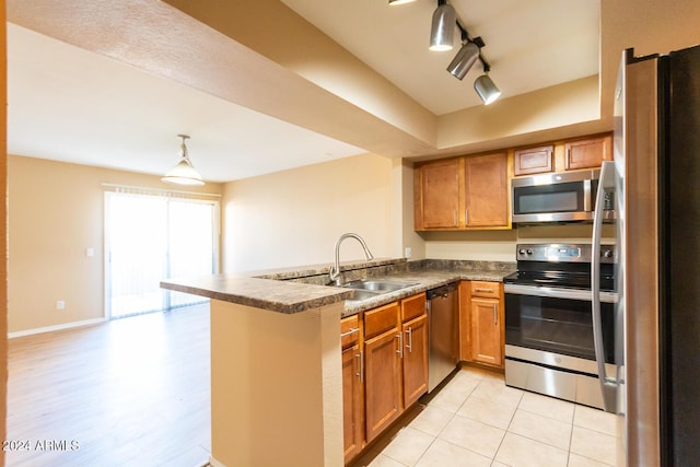 kitchen with rail lighting, sink, light hardwood / wood-style flooring, appliances with stainless steel finishes, and kitchen peninsula