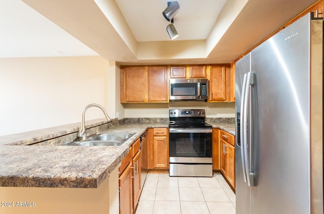 kitchen with sink, light tile patterned floors, appliances with stainless steel finishes, a tray ceiling, and kitchen peninsula