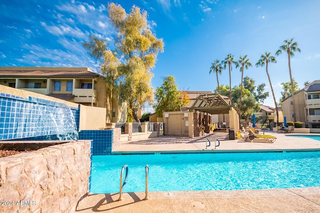 view of pool featuring a pergola, pool water feature, and a patio