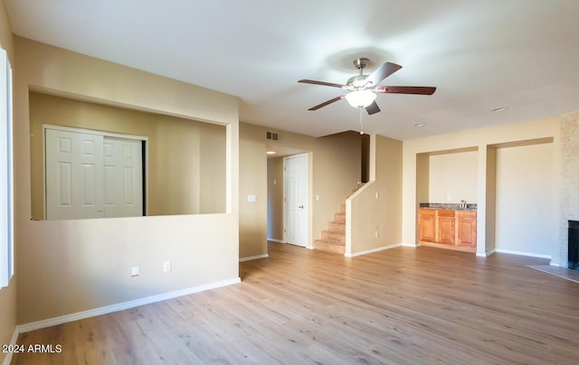 unfurnished room featuring a fireplace, light hardwood / wood-style flooring, ceiling fan, and sink