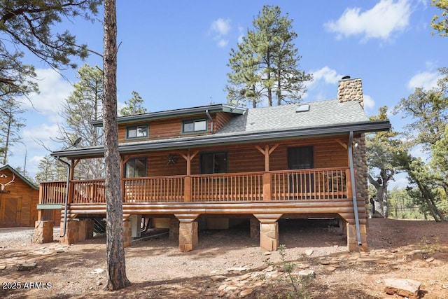 back of house with covered porch, roof with shingles, and a chimney