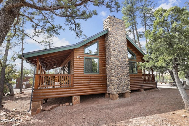 view of home's exterior featuring faux log siding, driveway, and a chimney