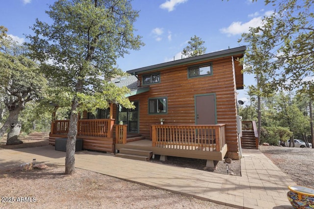 rear view of property with a patio area, faux log siding, and a wooden deck