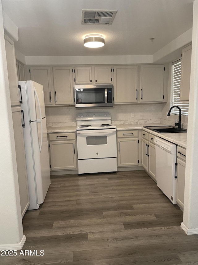 kitchen with visible vents, dark wood finished floors, light countertops, white appliances, and a sink