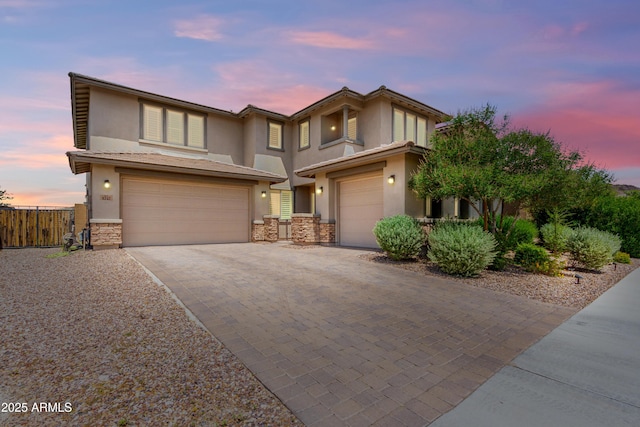 view of front of house featuring a garage, stucco siding, stone siding, and driveway