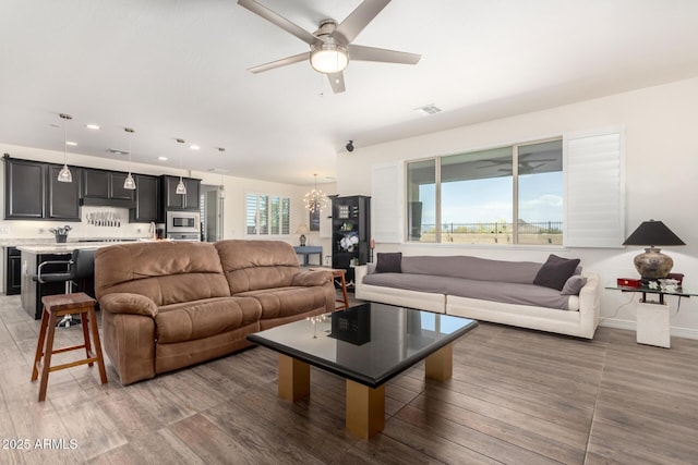living room with ceiling fan with notable chandelier, wood finished floors, visible vents, recessed lighting, and baseboards
