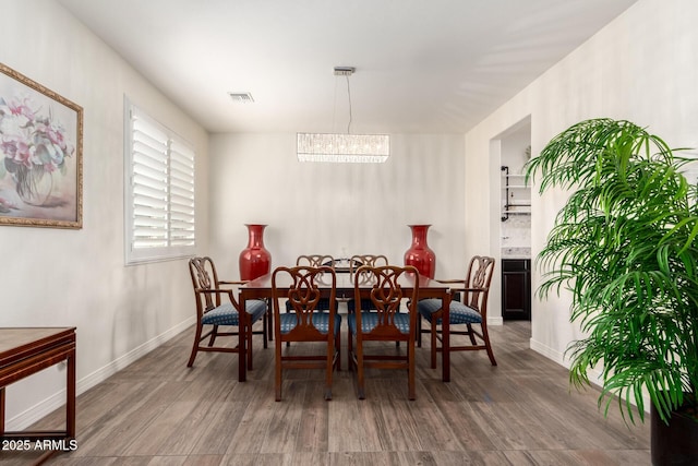 dining space featuring an inviting chandelier, baseboards, visible vents, and wood finished floors