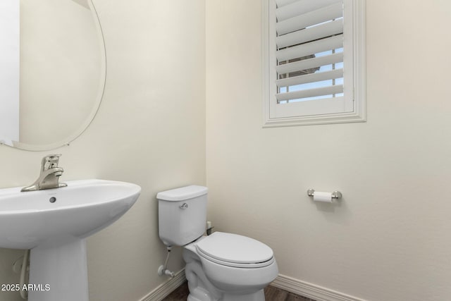 bathroom featuring baseboards, toilet, a sink, and wood finished floors