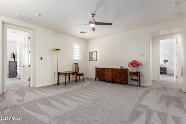 interior space with baseboards, visible vents, ceiling fan, and carpet