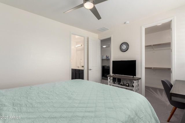bedroom with a closet, carpet, baseboards, ceiling fan, and a walk in closet