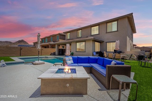 back of property at dusk featuring a patio, a fenced in pool, stucco siding, and a fenced backyard