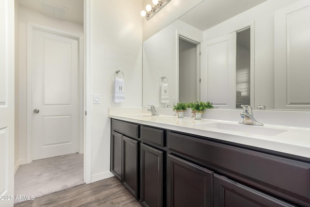 full bathroom with double vanity, visible vents, wood finished floors, and a sink
