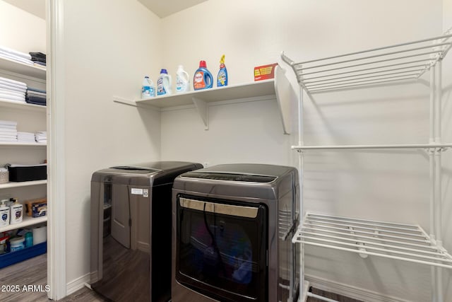 clothes washing area featuring washing machine and dryer, laundry area, baseboards, and wood finished floors