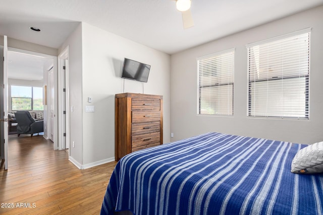 bedroom featuring baseboards, wood finished floors, and a ceiling fan