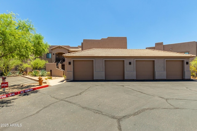 view of front of home with a tiled roof, community garages, and stucco siding