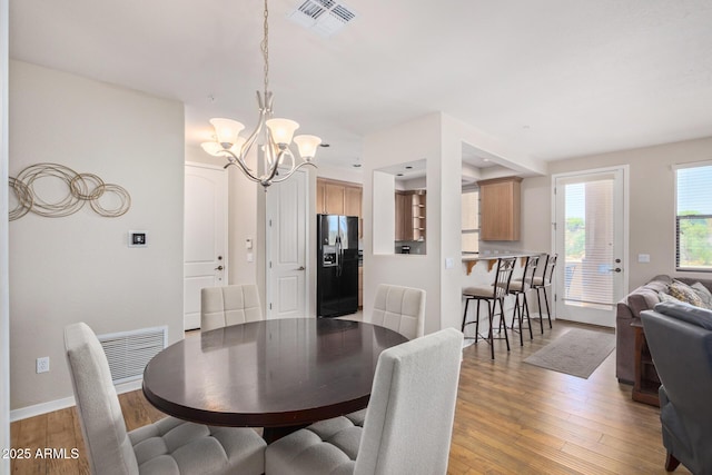 dining space with light wood-type flooring, visible vents, baseboards, and a chandelier