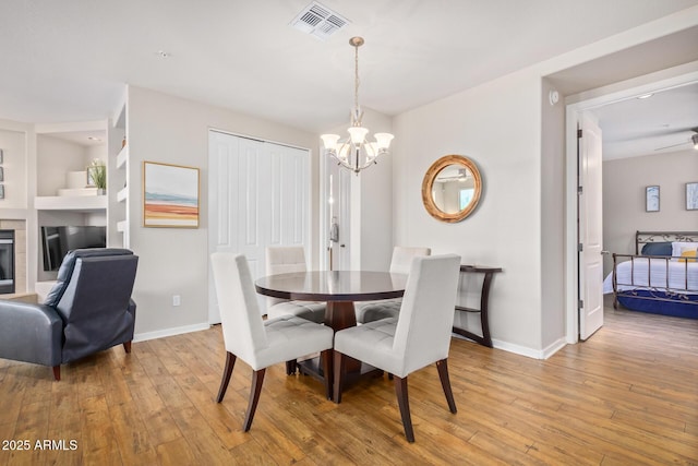 dining room with an inviting chandelier, light wood-style floors, visible vents, and baseboards