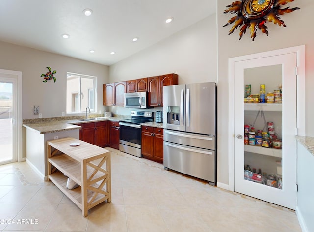 kitchen featuring light tile patterned floors, light stone counters, appliances with stainless steel finishes, vaulted ceiling, and a sink