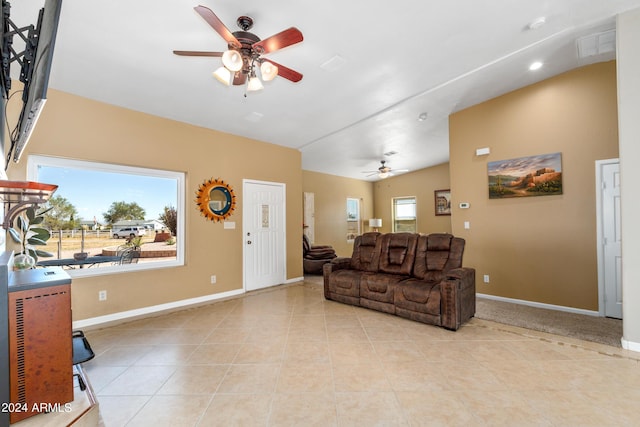living room featuring a ceiling fan, light tile patterned flooring, vaulted ceiling, and baseboards