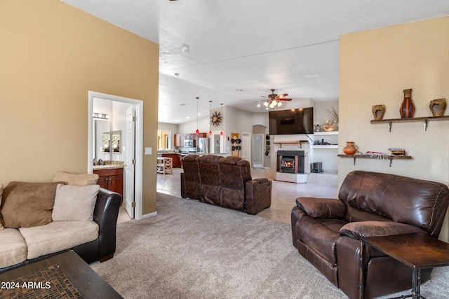living area with lofted ceiling, a warm lit fireplace, light colored carpet, and ceiling fan