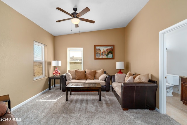 living room with vaulted ceiling, light carpet, a ceiling fan, and baseboards