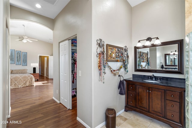 bathroom featuring baseboards, a ceiling fan, wood finished floors, vaulted ceiling, and vanity