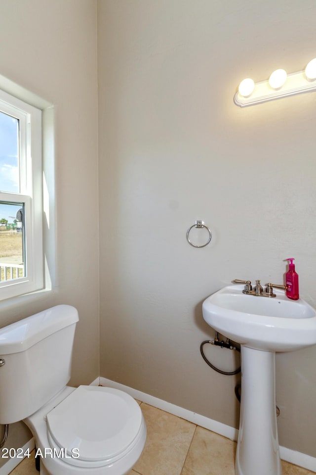 half bath featuring baseboards, a sink, toilet, and tile patterned floors