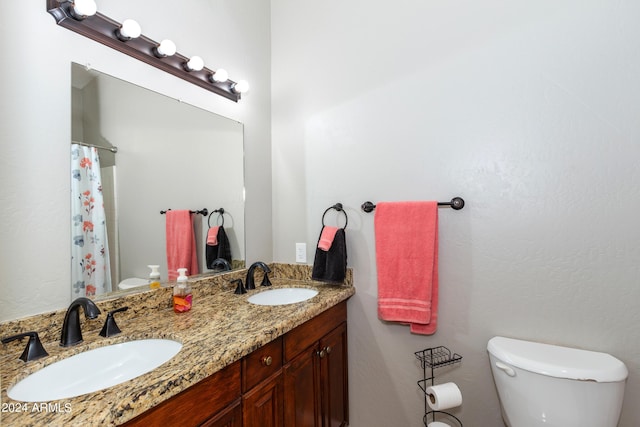 bathroom with double vanity, curtained shower, a sink, and toilet