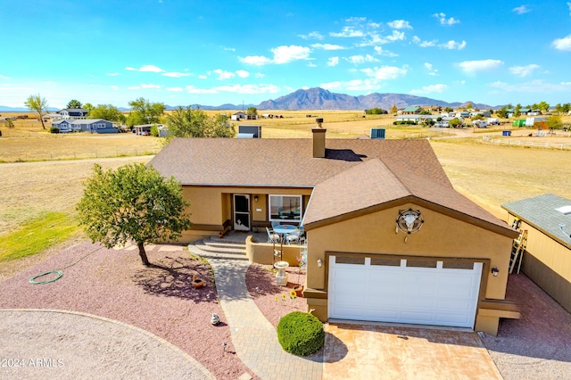 ranch-style house featuring a mountain view, a garage, driveway, roof with shingles, and stucco siding