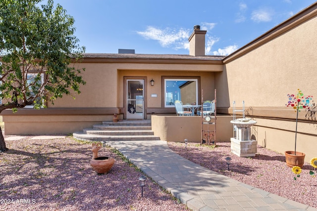 entrance to property with a chimney and stucco siding
