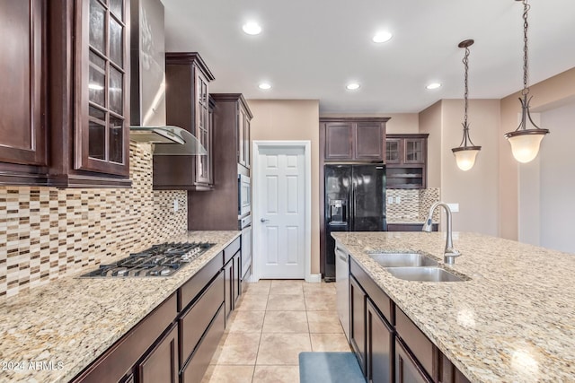 kitchen featuring wall chimney exhaust hood, dark brown cabinets, stainless steel appliances, sink, and hanging light fixtures