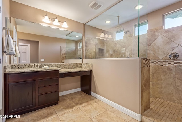 bathroom with tile patterned flooring, vanity, and tiled shower