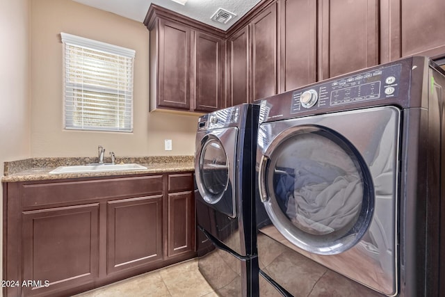 laundry room with cabinets, light tile patterned flooring, washing machine and dryer, and sink