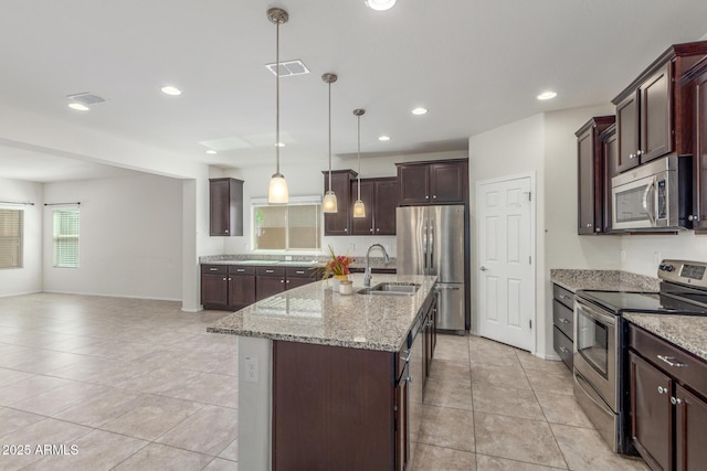 25945 W Runion Dr, Buckeye, AZ 85396 - kitchen with stainless steel appliances, light tile patterned floors, light stone countertops, dark brown cabinets, and a kitchen island with sink