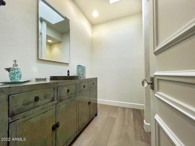 bathroom featuring vanity, hardwood / wood-style floors, and a skylight