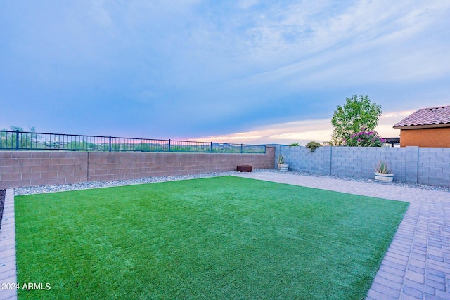 yard at dusk featuring a patio