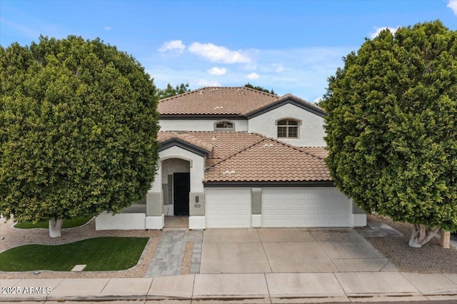 mediterranean / spanish-style home with concrete driveway, a tiled roof, an attached garage, and stucco siding