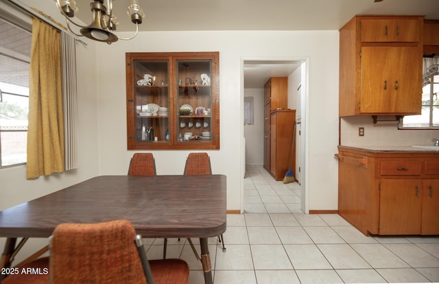 dining room featuring an inviting chandelier, light tile patterned floors, and baseboards