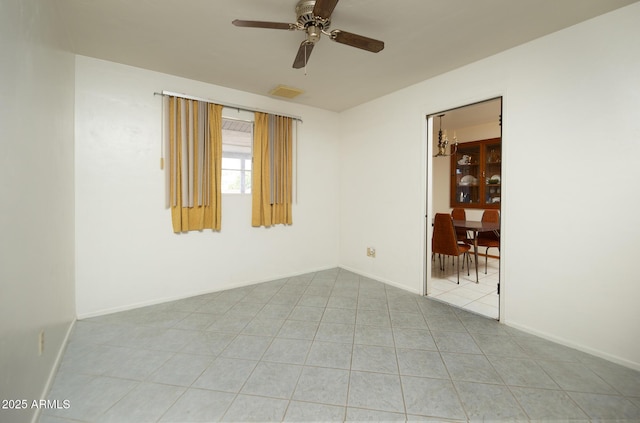 empty room with tile patterned flooring, visible vents, a ceiling fan, and baseboards