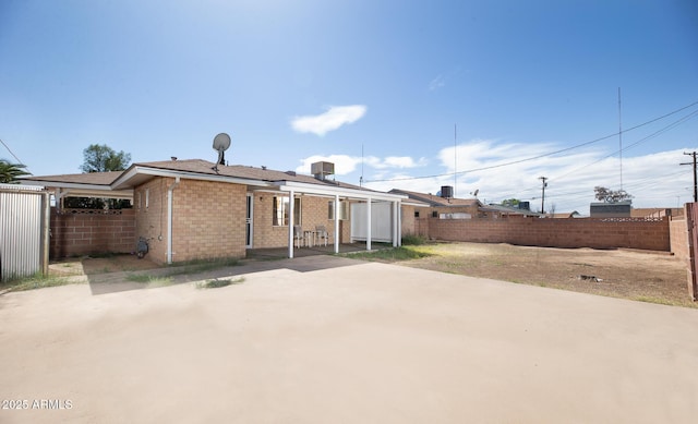 rear view of property featuring brick siding, a fenced backyard, and a patio area