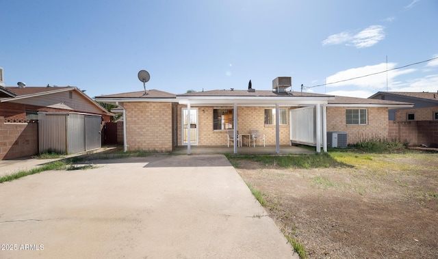 view of front of home featuring a porch, cooling unit, and brick siding